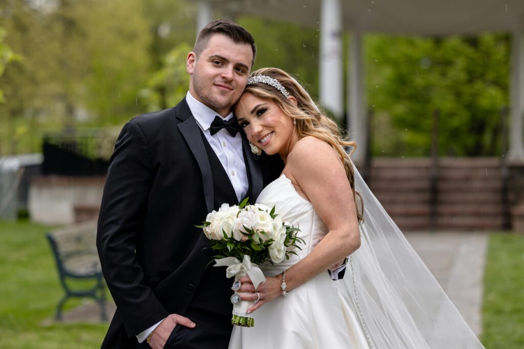 A joyful wedding couple posing in a beautiful garden setting.